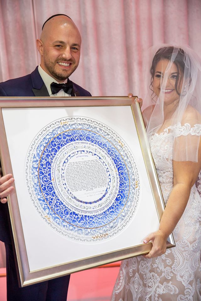 A couple excitedly discussing their vision for their custom Ketubah with an artist.